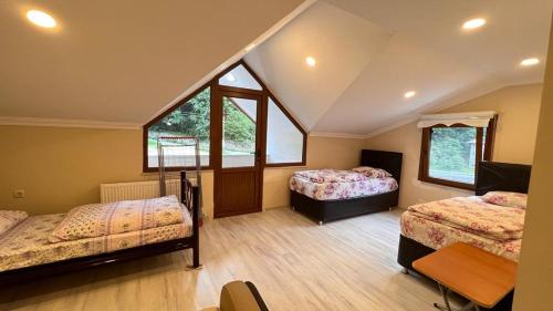a attic bedroom with two beds and two windows at Bahar Villa Pansiyon in Uzungöl