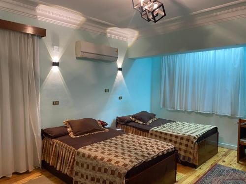 two beds in a room with blue walls at Luxurious, fully furnished and well-equipped apartment with modern amenities, stunning views, and convenient location for remote work or studying from home in Cairo