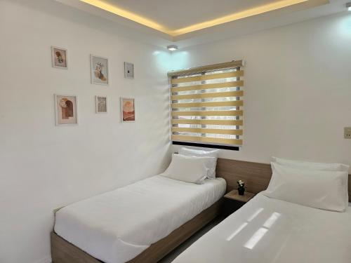 2 camas en una habitación con paredes blancas y ventana en MGS Property en General Santos