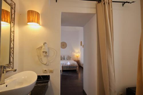 uma casa de banho com um lavatório, um espelho e uma cama em Riad Pierres et Saveurs Soleil em Marrakech
