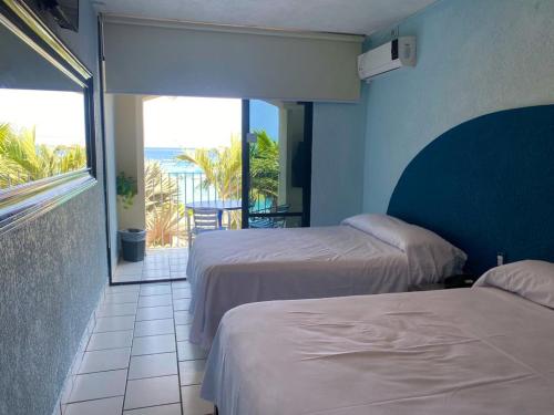two beds in a room with a view of the ocean at Acamar Beach Resort in Acapulco