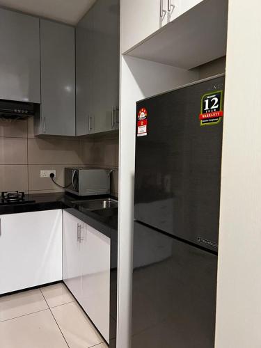a kitchen with white cabinets and a black refrigerator at Zetapark, The Loft in Kuala Lumpur