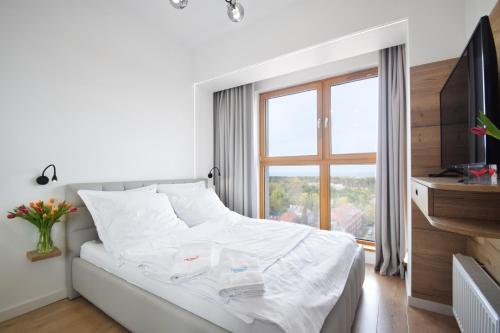a white bed in a room with a window at Horizon.12 Platan Tower in Świnoujście