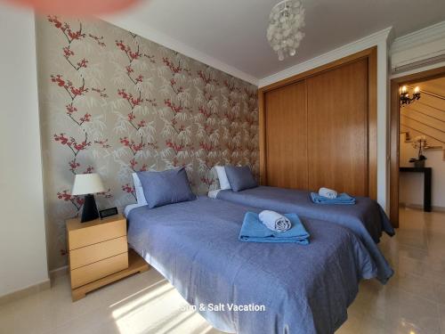 1 dormitorio con 2 camas con sábanas azules y pared en Cabanas de Tavira Smashing 2 bed, 2 bath, Duplex Penthouse en Cabanas de Tavira