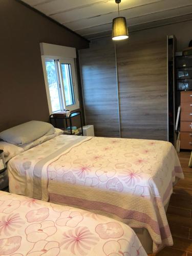 una camera con due letti con fiori rosa di La Cabaña del tío Tom a Veigue