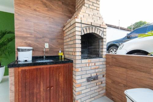 uma cozinha exterior com um forno de tijolos numa garagem em Pirangi Prime #05 - Triplex Vista Mar em Pirangi do Norte por Carpediem em Parnamirim