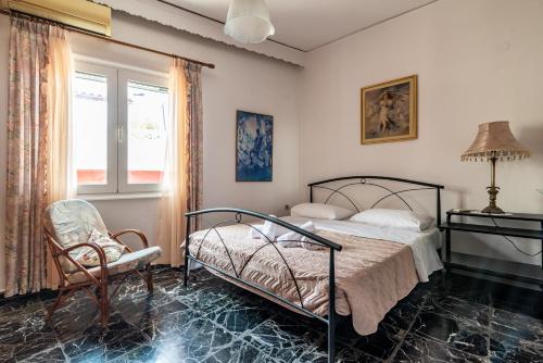 a bedroom with a bed and a chair and a window at Cretan Village Renovated House in Heraklio Town