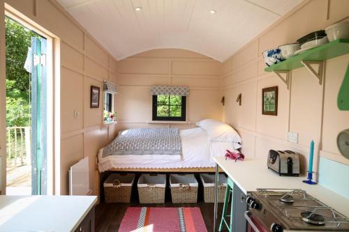 a tiny house with a bed in a kitchen at Lapin Cottage in Long Bredy