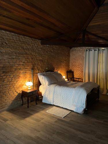 a bedroom with a bed and a brick wall at Vila Adega Maravilha in São Roque