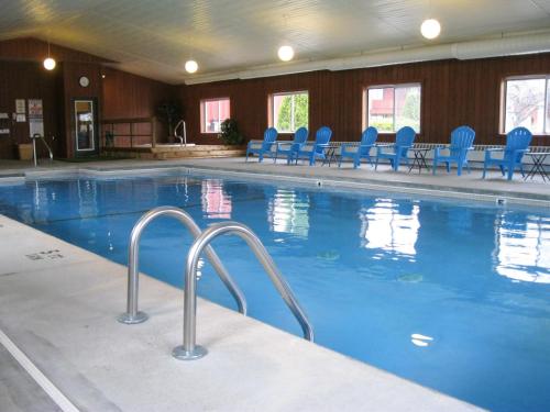 una gran piscina con sillas azules en un edificio en Cedar Hill Lodge en Saint Ignace