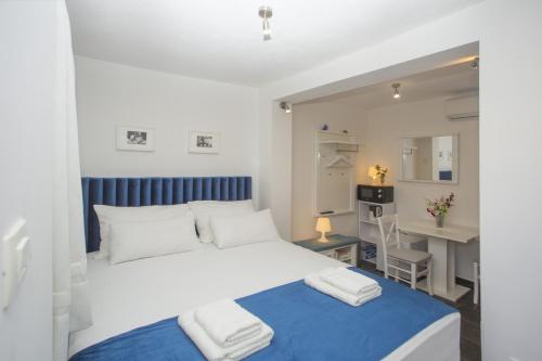 a bedroom with a white bed and a desk and a table at Guest House Kušeta in Split