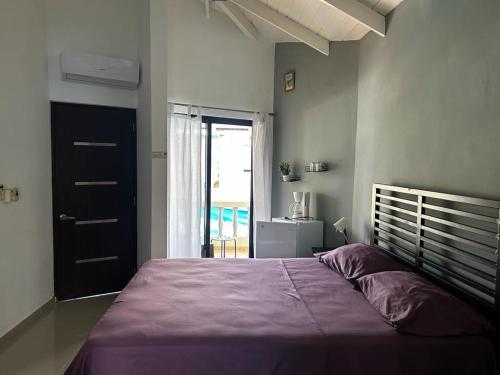 a bedroom with a large bed with a purple blanket at Casa MIA in Cabarete
