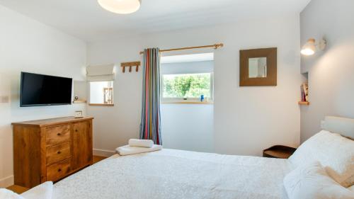 a bedroom with a bed and a tv and a window at Pipistrelle Barn in Kniveton