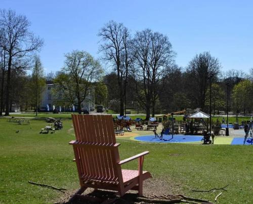 uma cadeira de madeira num parque com um parque infantil em Attefallshus Alingsås / Dammen. em Alingsås