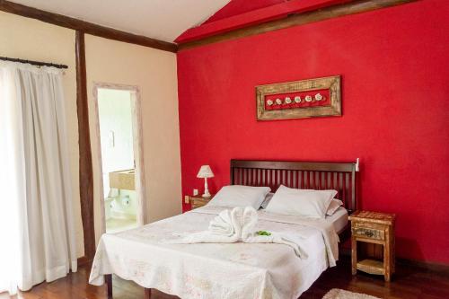 a bedroom with red walls and a bed with towels on it at Pousada Terraço Penedo in Penedo