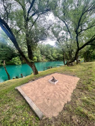 a fire pit in the grass next to a river at Pool & River House - Lazara in Danilovgrad
