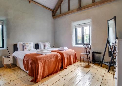 um quarto com uma cama grande e um cobertor laranja em Straw Bale Cottage em Haughley