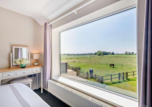 una camera da letto con una grande finestra con vista su un pascolo di cavalli di Swallows Return - Colkirk a Colkirk