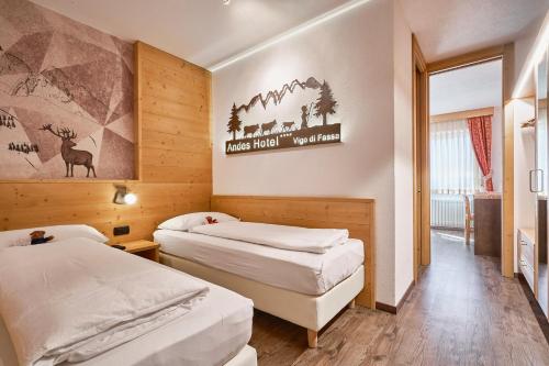 una camera d'albergo con due letti e una foto a parete di Family Hotel Andes - Only for Family a Vigo di Fassa