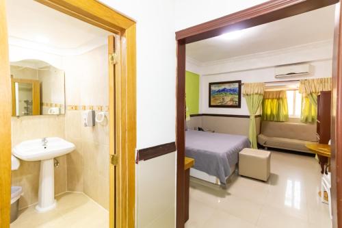 a bedroom with a bed and a sink and a bathroom at Hotel La Casona Dorada in Santo Domingo