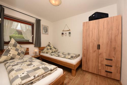 - une chambre avec 2 lits et une armoire en bois dans l'établissement Ferienwohnung Allgäuer Bergnest, à Fischen im Allgäu