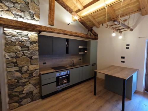 cocina con pared de piedra y mesa de madera en Appartamenti il bersaio Alloggio 4, en Sambuco