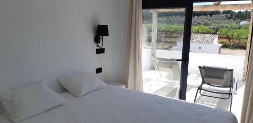 a bedroom with a white bed and a balcony at Casa Padel El Perello in Perelló