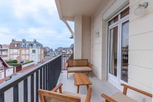 - un balcon avec des chaises et un banc dans un bâtiment dans l'établissement 2-bedroom apartment with balcony near Hippodrome, à Deauville