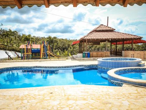 a swimming pool with a playground and a slide at CABAÑA Y RESTAURANTE CAMPESTRE EL MIRADOR COSTEÑO in Turbo
