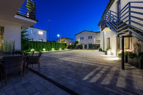 a patio with a table and chairs at night at Willa Lazur ADULTS ONLY in Międzyzdroje