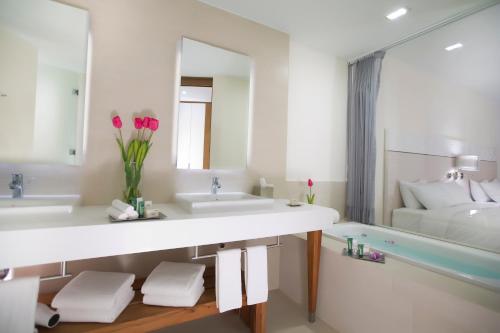 a bathroom with two sinks and a tub with pink flowers at Krystal Grand Puerto Vallarta - All Inclusive in Puerto Vallarta