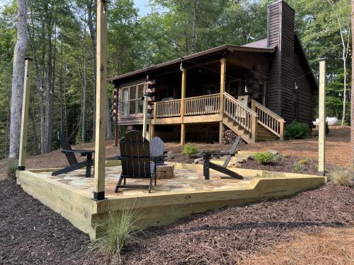 a log cabin with a porch and chairs on a deck at Fishful Thinking in Cherry Log