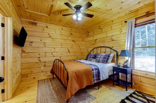 a log cabin bedroom with a bed and a ceiling fan at Fishful Thinking in Cherry Log