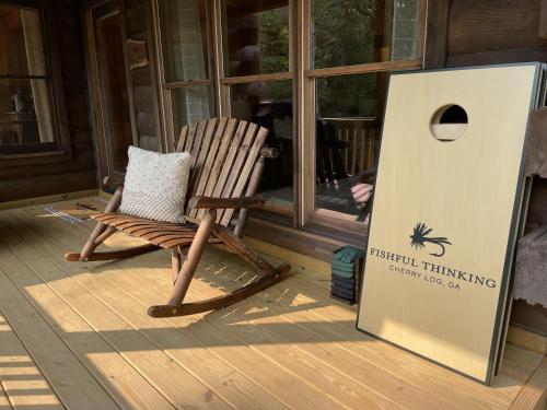 a rocking chair sitting on a porch next to a sign at Fishful Thinking in Cherry Log