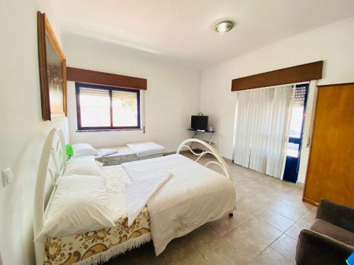 a bedroom with a white bed and a window at Come Inn Sesimbra in Quinta do Conde