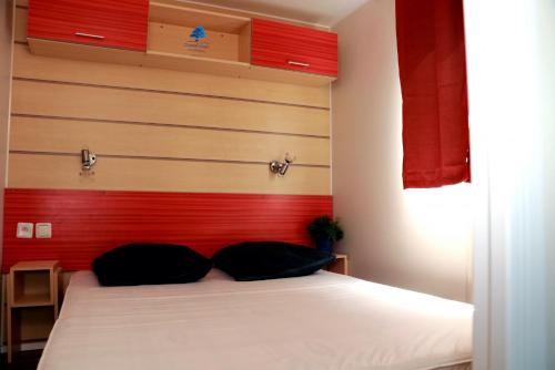 a bedroom with a white bed with a red headboard at Mobilhome «Perle marine»*6 personnes *3 Chambres*TV in Sigean