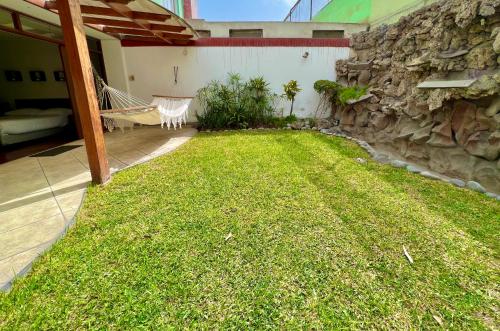 a backyard with a rock wall and a hammock in the grass at Lima Mini Aparts Monterrico - Cerca Embajada EEUU in Lima