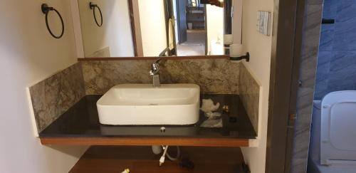 a sink in a bathroom with a mirror at Vue D'en Haut, Ooty in Ooty