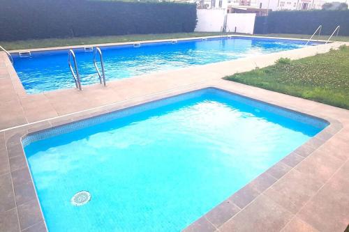 een groot zwembad met blauw water bij Vistas al mar con jardín privado, piscina y padel in Foz