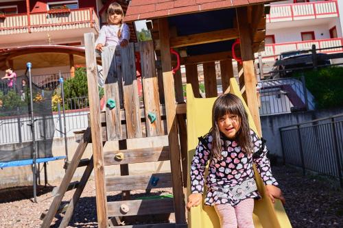 a young girl sitting on a slide at a playground at Family Hotel Andes - Only for Family in Vigo di Fassa