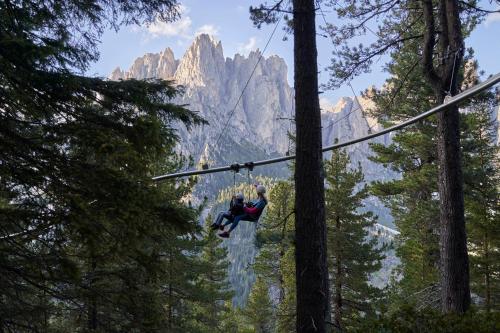 a person on a zip line in the mountains at Family Hotel Andes - Only for Family in Vigo di Fassa