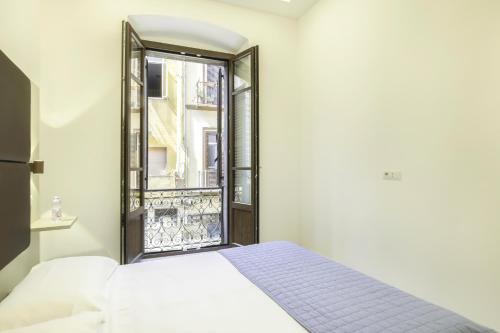 ein Schlafzimmer mit einem Bett und einem offenen Fenster in der Unterkunft La Suite Cagliari - Cagliari centro in Cagliari
