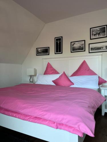 a large bed with pink sheets and pillows at Papenburger Gästehaus in Papenburg