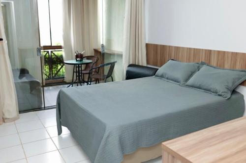 a bedroom with a bed and a table and a balcony at Flat na Fazenda Monte Castelo Gravatá Sairé - Mod 12 - Flat 9 in Gravatá
