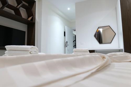 a bedroom with a white bed and a mirror at The Honeycomb Boutique Hotel in Golem