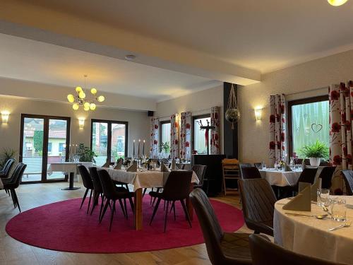 uma sala de jantar com mesas, cadeiras e janelas em Freigeist • Pension & Brasserie em Witzin