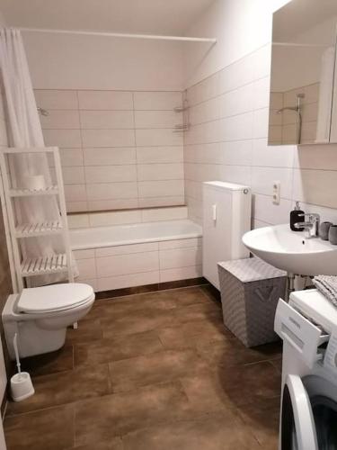 a bathroom with a toilet and a tub and a sink at cozy City Apartment in Senftenberg