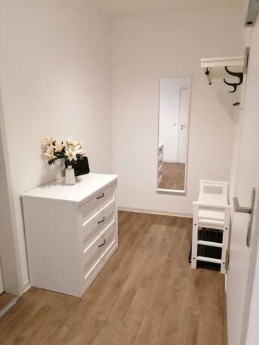 a white room with a dresser with flowers on it at cozy City Apartment in Senftenberg