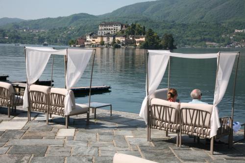 a man and a woman sitting in chairs by a lake at Hotel San Rocco in Orta San Giulio