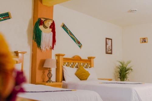 a bedroom with two beds with white sheets at Hotel Carnaval in Huejotzingo